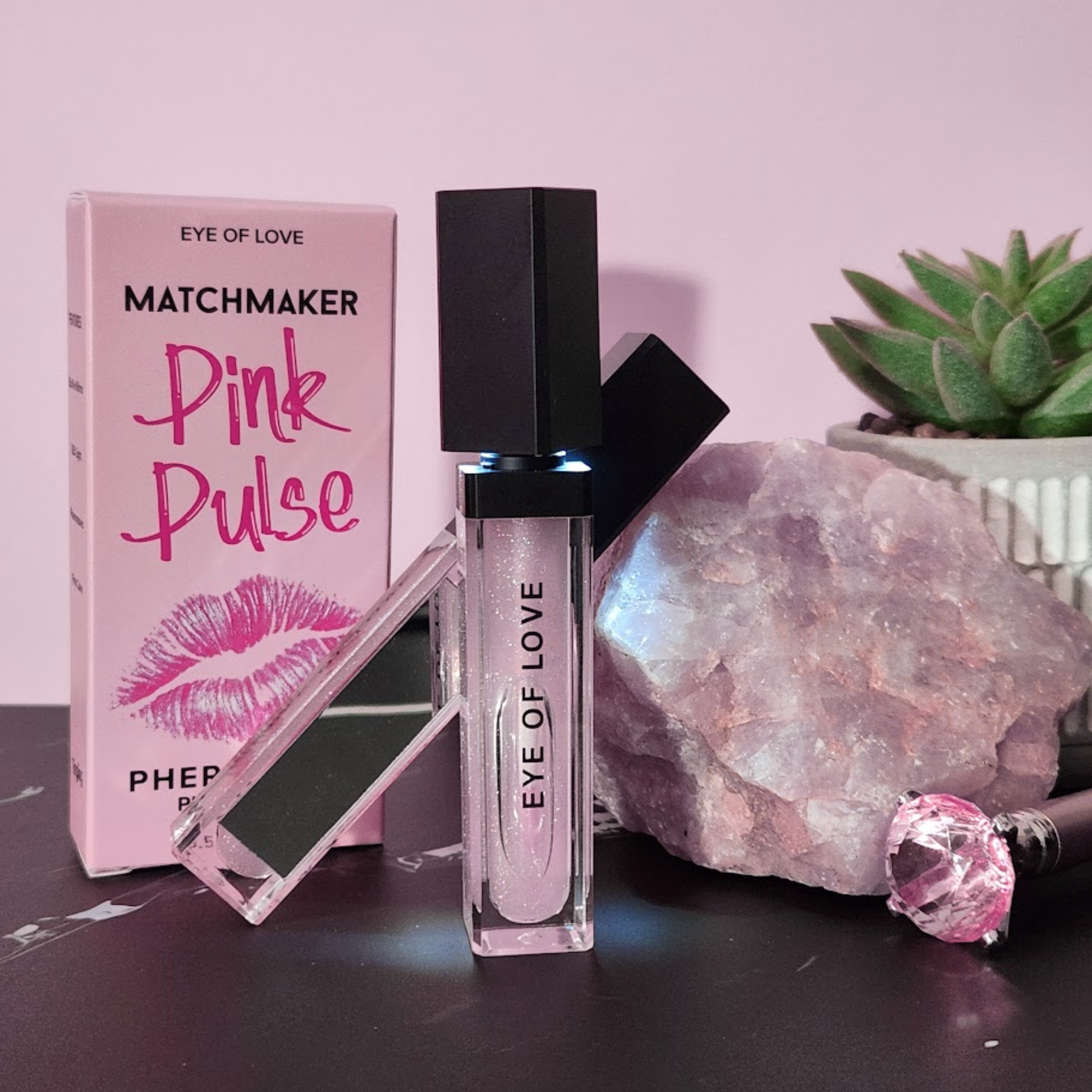 Pink perfume bottle with packaging and decorative elements on a pink background